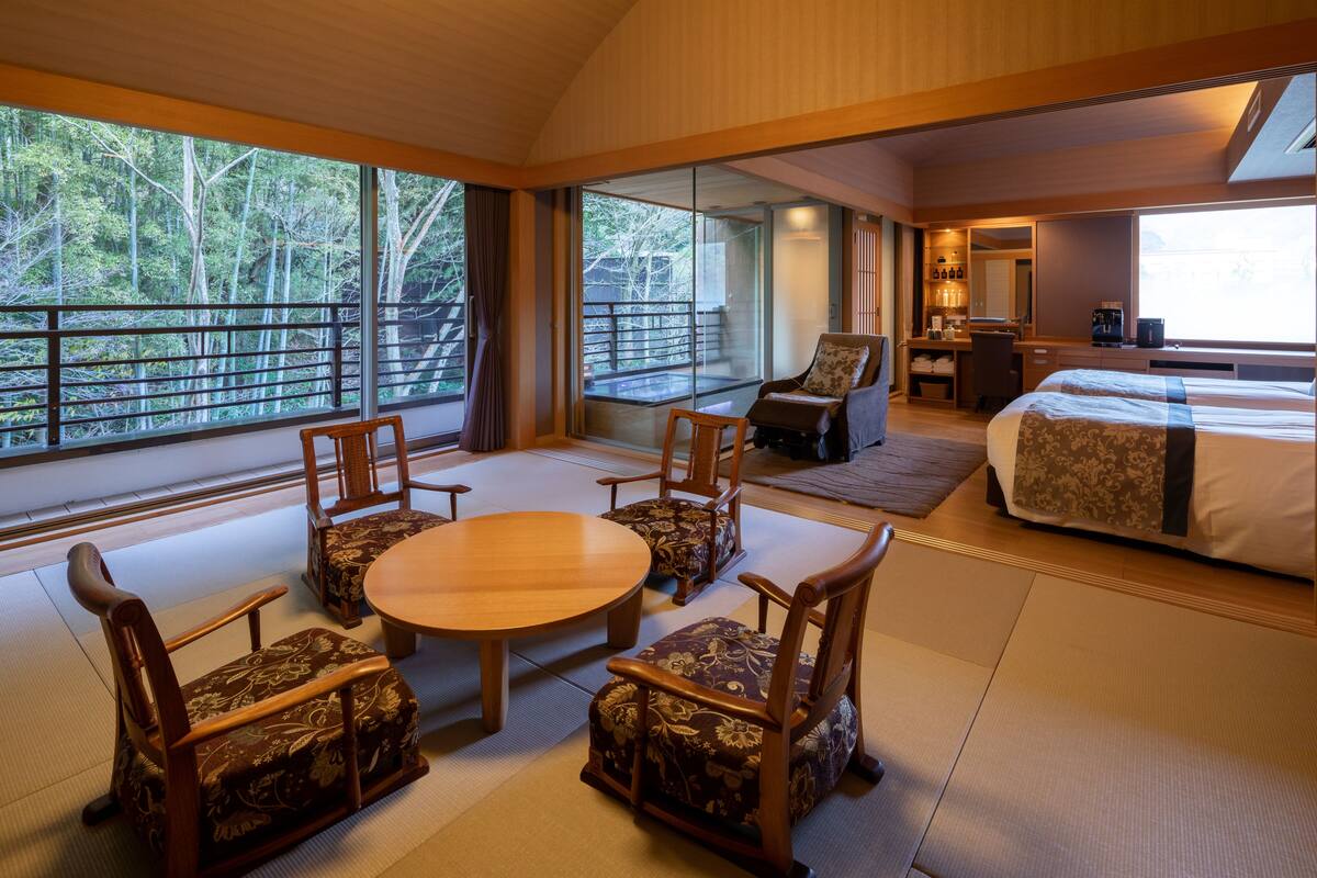 A spacious room with tatami flooring, a round table, and traditional wooden chairs.