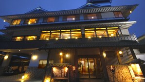 Edifici tradicional japonès amb diversos nivells i finestrals grans, il·luminat per una llum interior càlida.