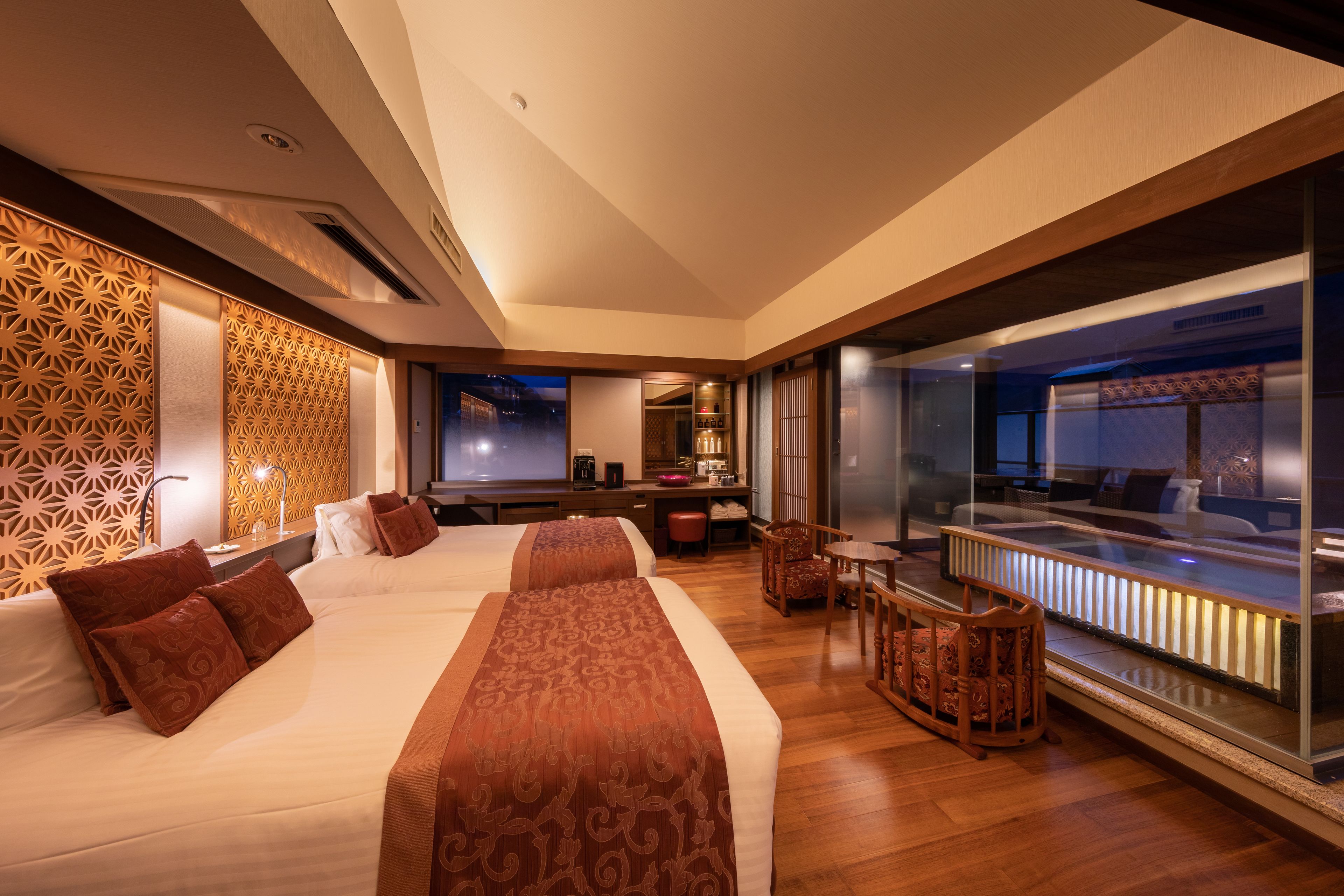 A modern hotel room with a large bed, a desk, and a seating area.