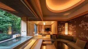A modern interior with a glass pool, wooden flooring, a sofa, and a TV in the background. - Hakone Kamon (Hakone)