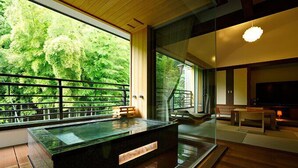 A modern interior with a large window overlooking lush greenery, a wooden deck, and a seating area with a TV. - Hakone Kamon (Hakone)