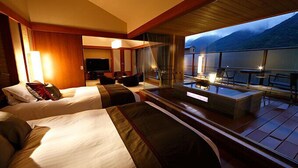 A hotel room with two beds, a TV, a balcony with a table and chairs, and a view of mountains. - Hakone Kamon (Hakone)