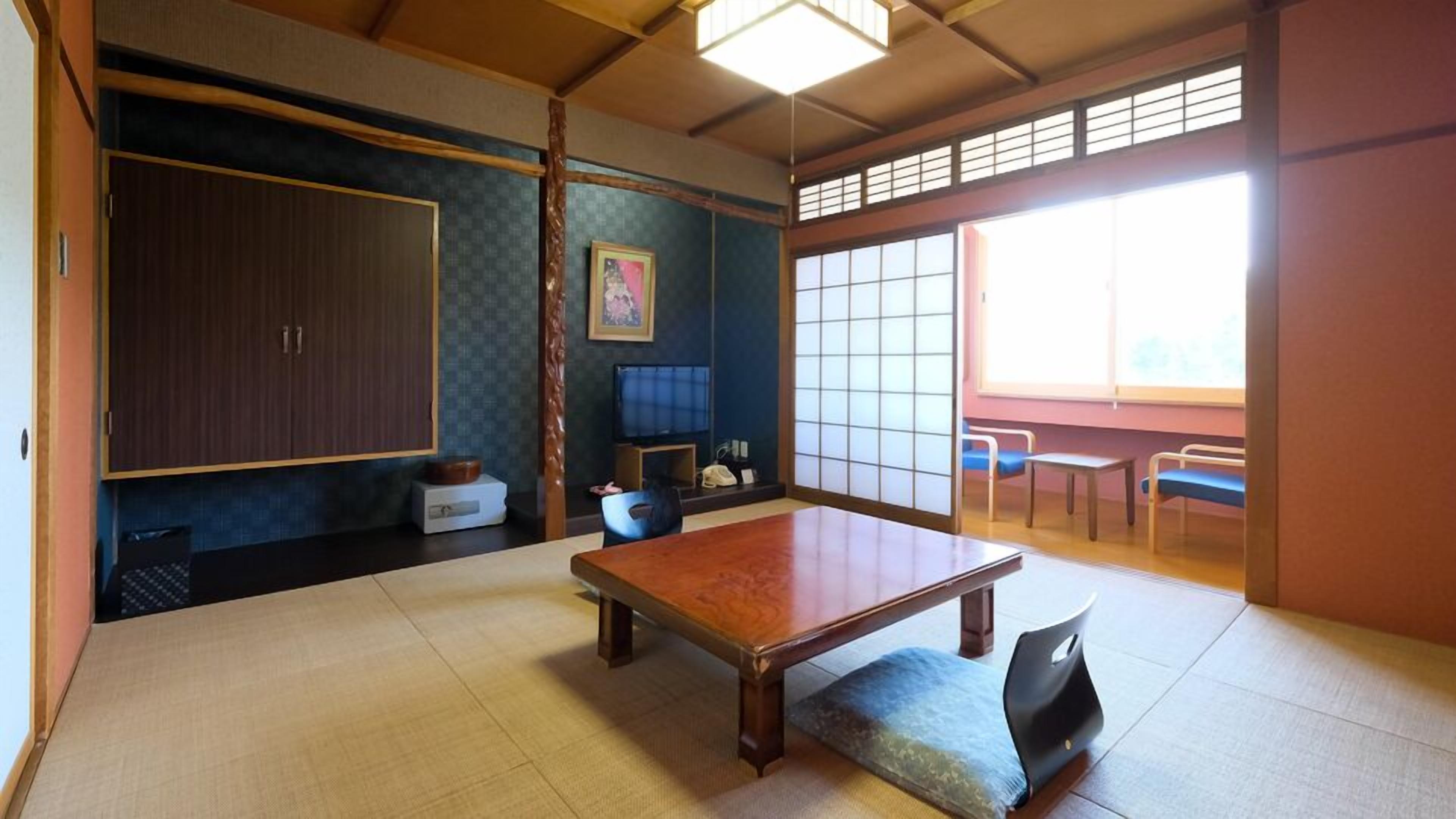 A traditional Japanese room with tatami flooring, a low table, a television, and sliding doors.