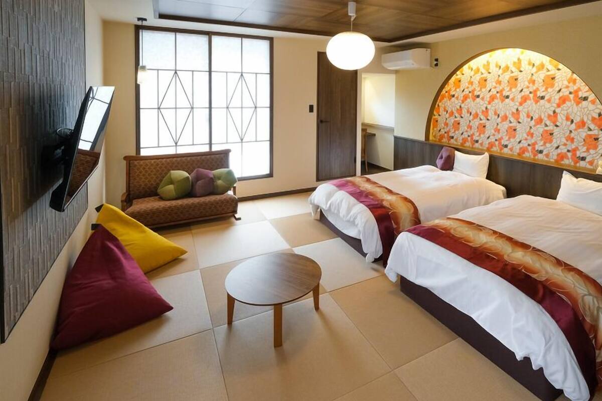 Une chambre d’hôtel avec deux lits, un canapé, une petite table et une grande fenêtre donnant sur un beau paysage.