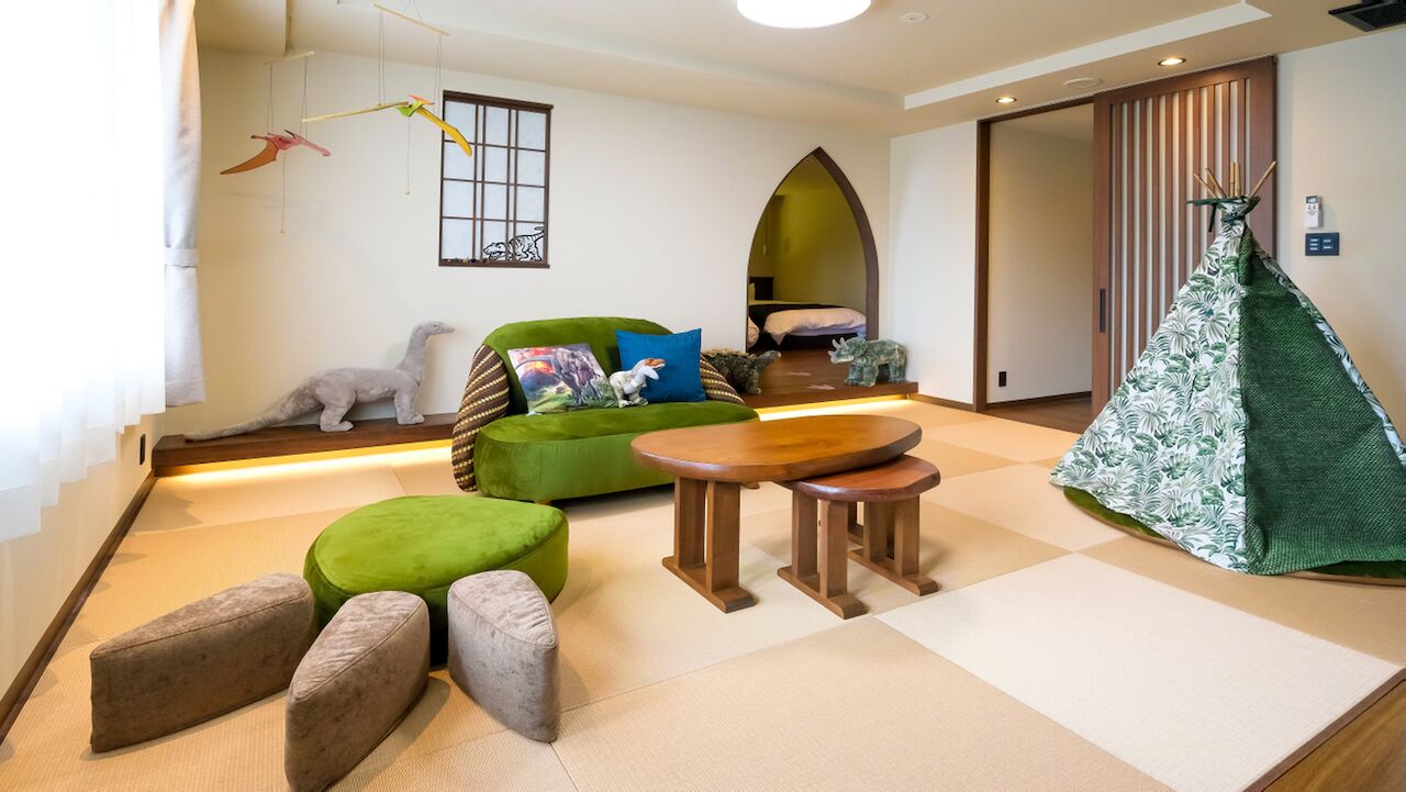 A room with a green sofa, a small round table, and a green tent-like structure.