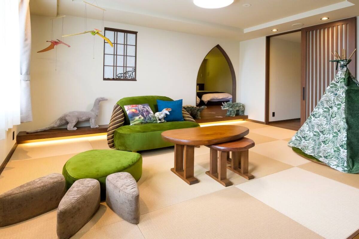 Une pièce avec un canapé vert, une petite table ronde et une structure verte en forme de tente.