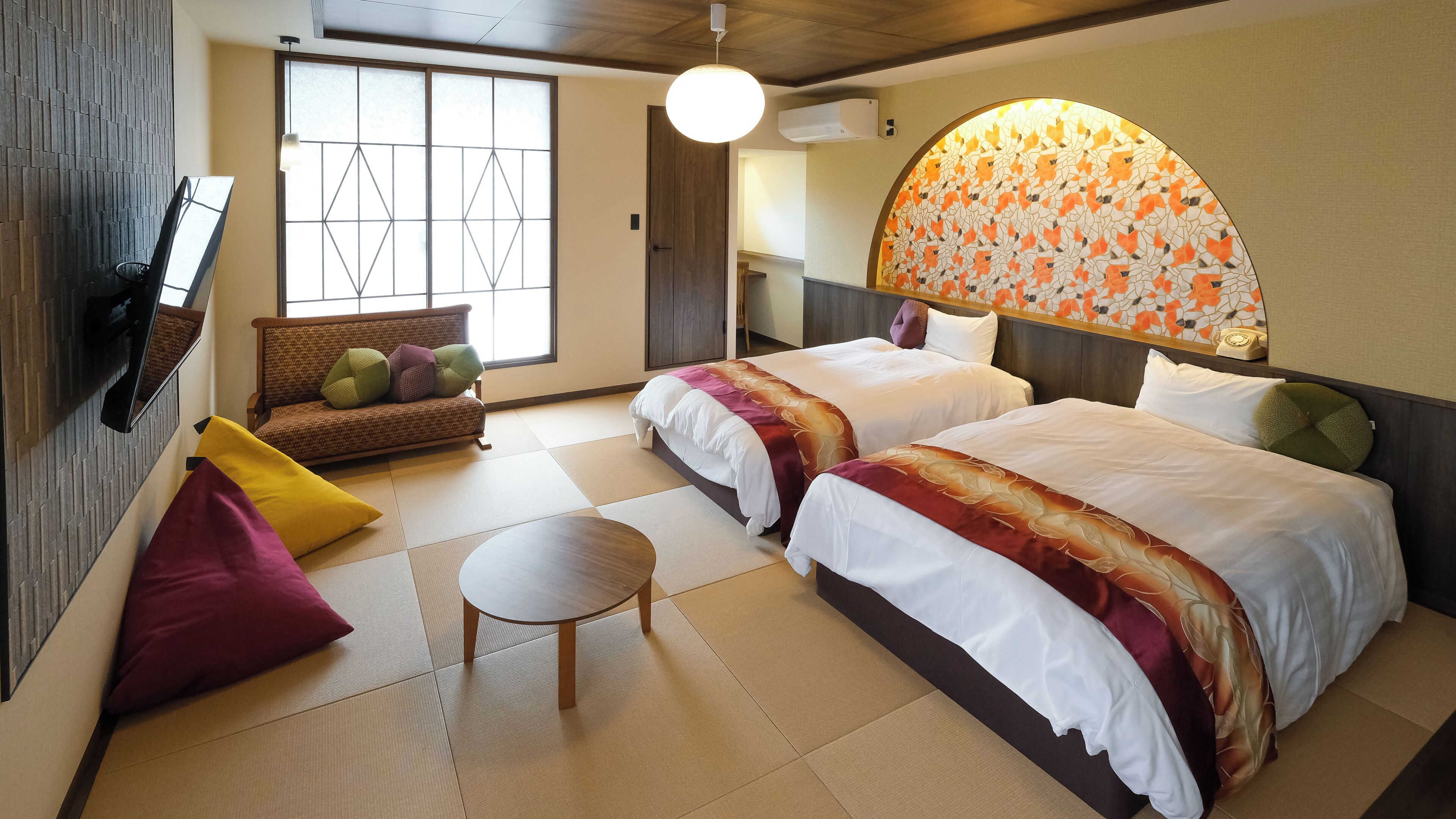 A hotel room with two beds, a sofa, a small table, and a large window.
