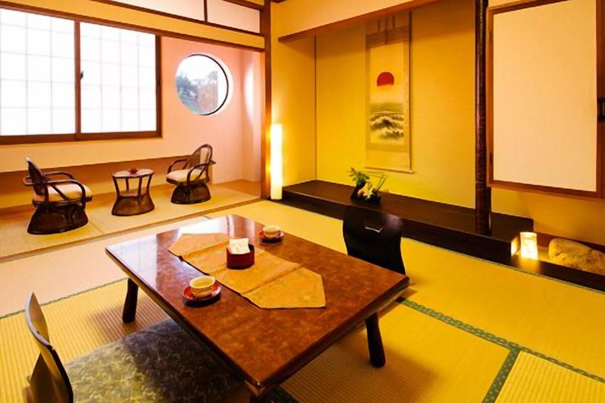 Une pièce de style japonais traditionnel, avec un sol recouvert de tatamis, une table basse avec des coussins et une porte coulissante.