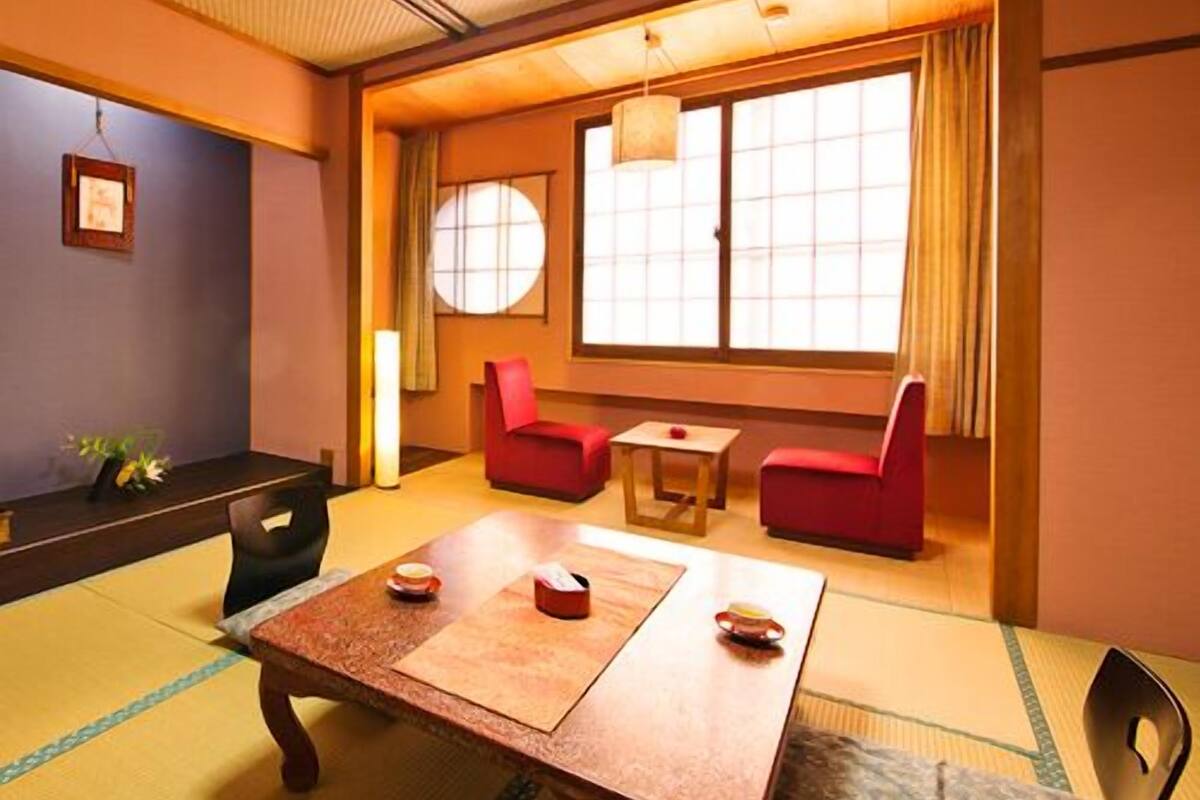 Une pièce de style japonais traditionnel, avec un sol recouvert de tatamis, une petite table basse avec des coussins et une porte coulissante donnant sur un paysage agréable.