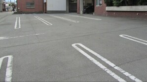 Ein Parkplatz mit markierten Stellplätzen und ein Gebäude mit einer Garageneinfahrt.
