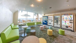 A room with green seating, vending machines, and a view of the ocean. - Kominato Miiri Onsen Hotel Green Plaza Kamogawa (Kamogawa)