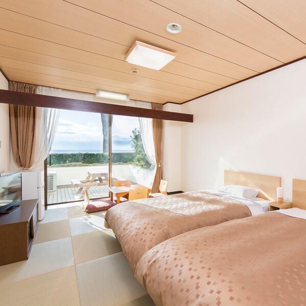 A hotel room with a bed, a desk, a chair, and a view of the outdoors.