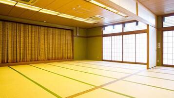 Ein Raum mit Tatami-Matten, Schiebetüren, einer Decke mit eingelassener Beleuchtung und einem traditionellen japanischen Shoji-Bildschirm.