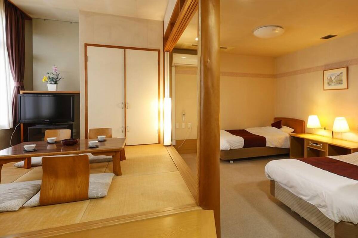Une chambre d’hôtel avec un coin repas, deux lits, une télévision et un tableau au mur.