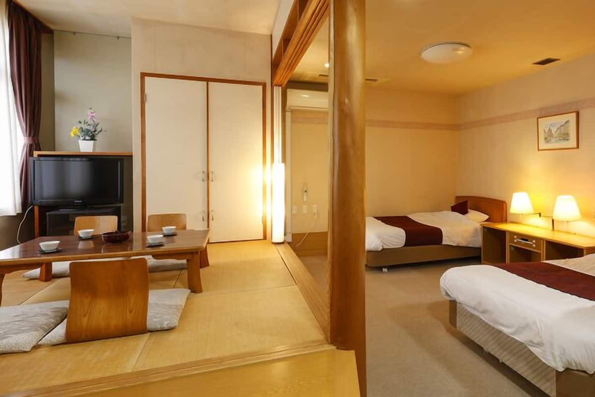 Ett hotellrum med en matplats, två sängar, en tv och en tavla på väggen.