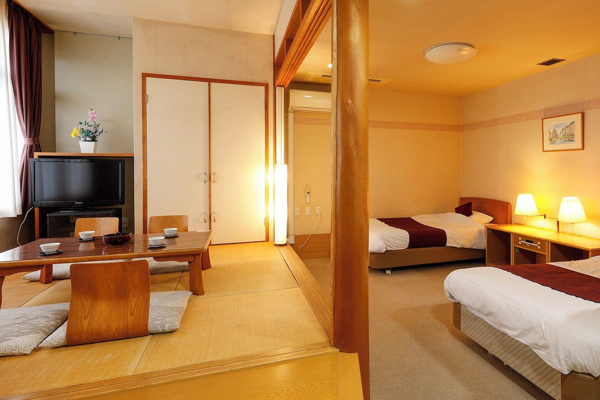 Une chambre d’hôtel comprenant un lit, des tables de chevet, une télévision et un coin repas avec une table et des chaises.
