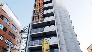 A multi-story building with a prominent yellow and blue sign indicating a parking garage. - Super Hotel Yokkaichi Ekimae (Yokkaichi)