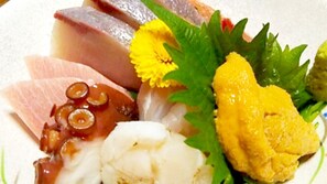 Une assiette contenant divers aliments, notamment du poisson, une fleur et un légume jaune.