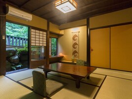 Una habitación japonesa tradicional con suelo de tatami, una mesa baja y puertas correderas.