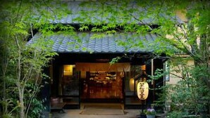 Een traditioneel Japans gebouw met een pannendak, een houten ingang en een naambord.