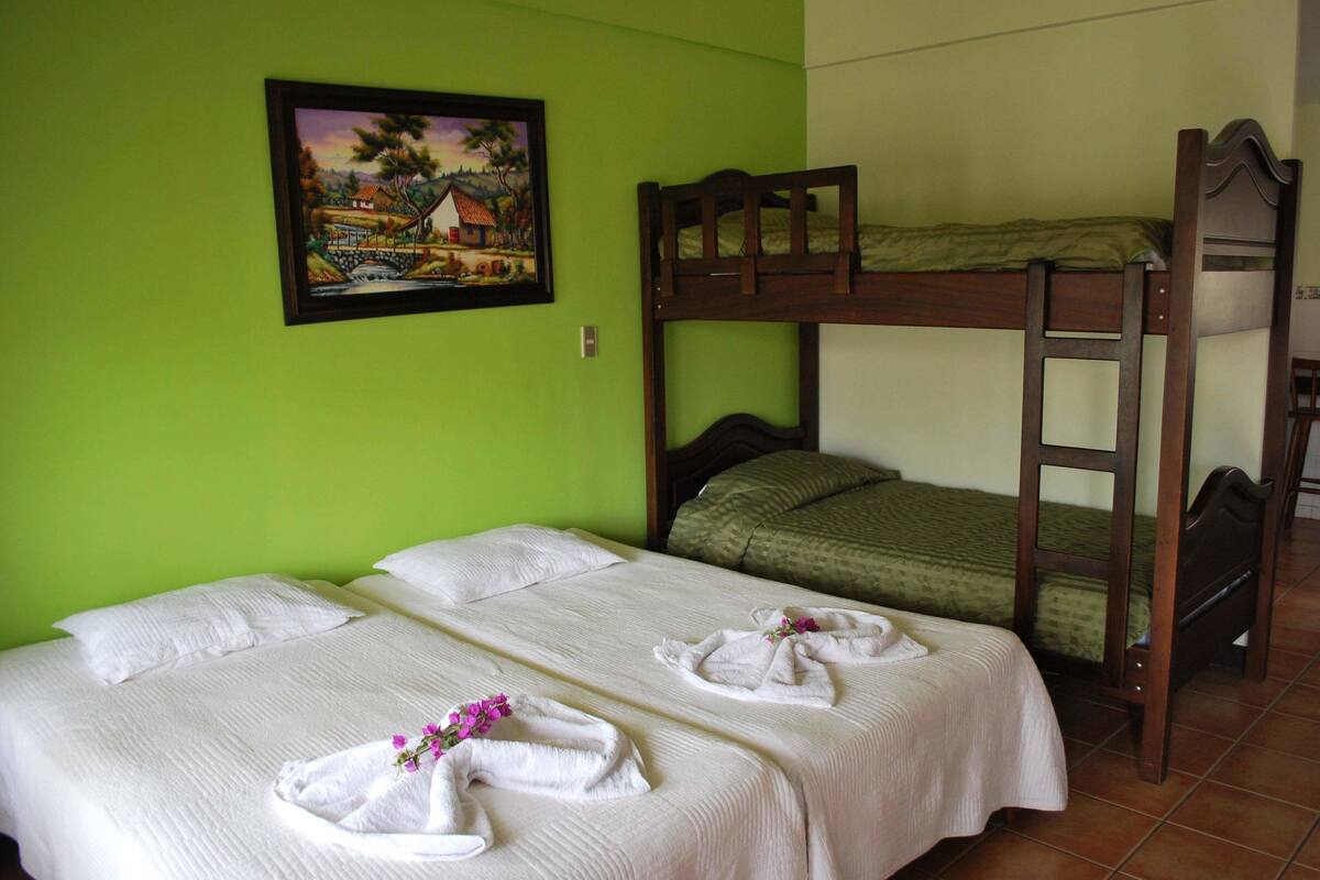 Una habitación con dos camas, una de ellas en literas, y un cuadro en la pared.