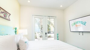 Quarto com cama, paredes brancas, uma porta e um letreiro do Margaritaville Resort.