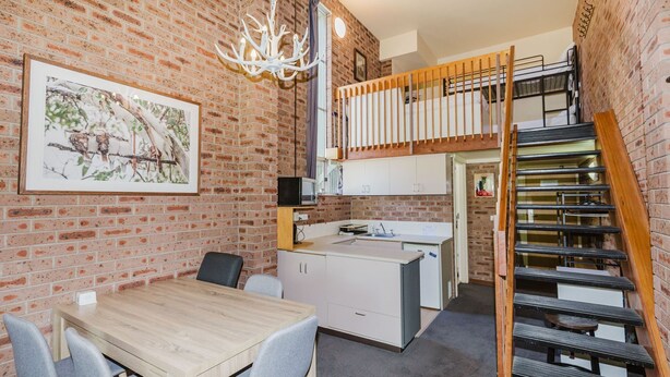 Eine kompakte Wohnung mit Essbereich, Küchenzeile und Schlafgalerie mit Treppe.