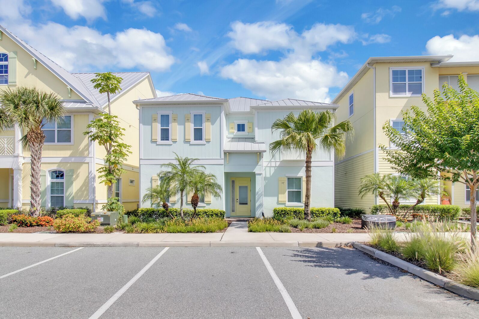 A row of two-story townhouses with a central entrance, parking lot, and well-maintained landscaping.
