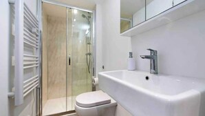 A modern bathroom with a glass shower enclosure, a white sink, and a toilet. - Notting Hill Chic sleeps 4-5 - 2 bedrms/2 bathrms-one en-suite + single SofaBed (London)