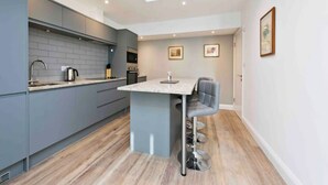 A modern kitchen with grey cabinets, a central island with bar stools, and a skylight. - Notting Hill Chic sleeps 4-5 - 2 bedrms/2 bathrms-one en-suite + single SofaBed (London)