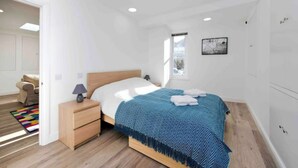 A modern bedroom with a wooden bed, bedside tables, a window, and a view of the outside. - Notting Hill Chic sleeps 4-5 - 2 bedrms/2 bathrms-one en-suite + single SofaBed (London)