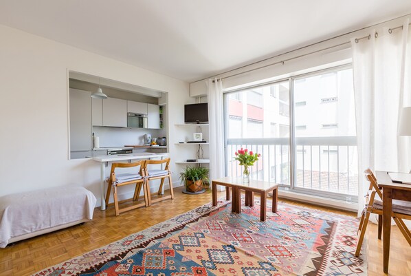 A compact living space with a kitchenette, a dining area, and a large window.