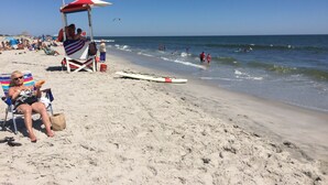 Une plage avec une tour de surveillance, des chaises longues et une planche de surf sur le sable.