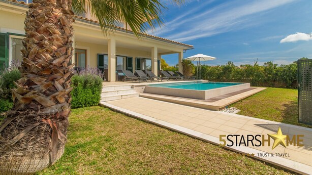 Uma casa moderna com piscina, alpendre coberto e palmeiras.
