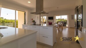 Cozinha moderna com uma ilha grande, eletrodomésticos embutidos e vista para o exterior.