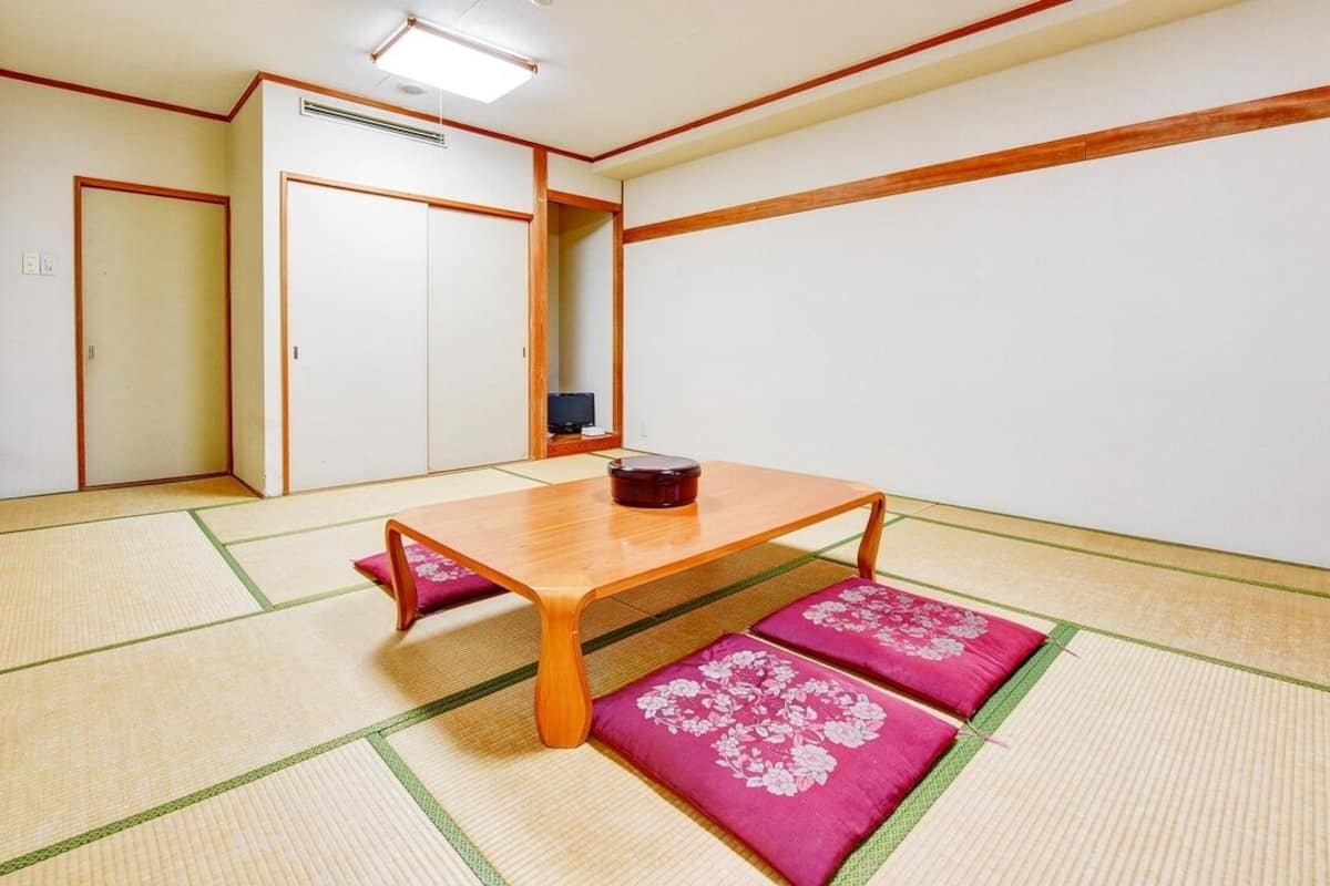 Ein traditioneller japanischer Raum mit Tatami-Boden, einem niedrigen Holztisch und einer Schiebetür.
