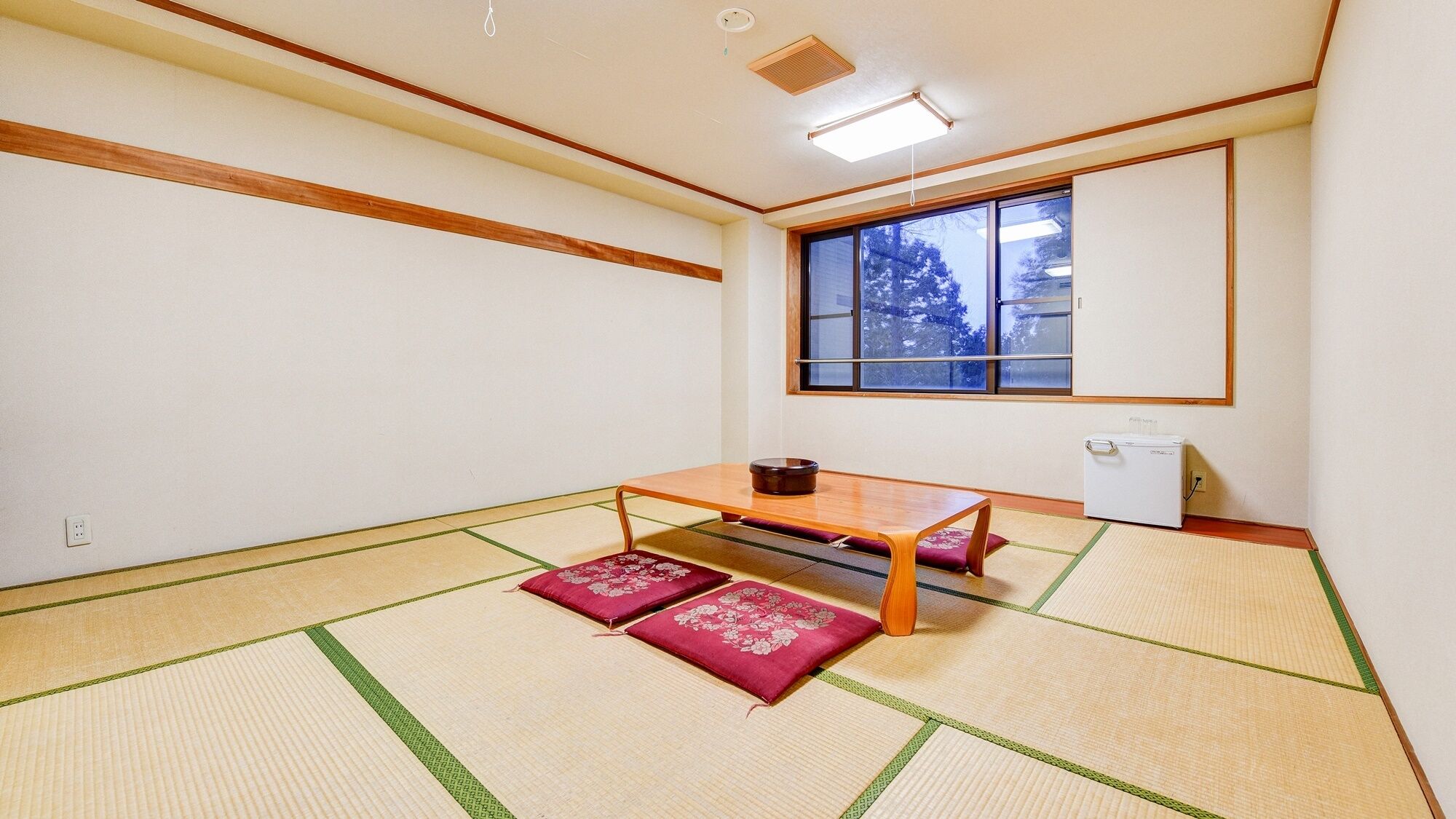 A traditional Japanese room with tatami flooring, a low table, and a futon bed.