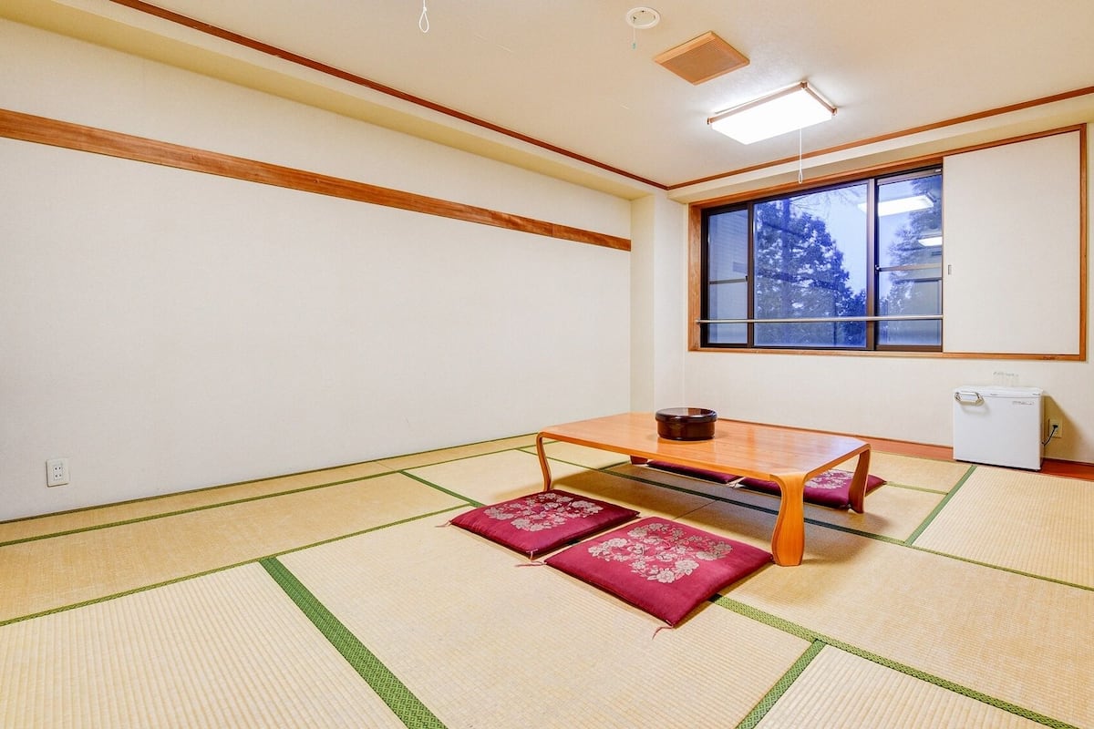 Ein traditioneller japanischer Raum mit Tatami-Boden, einem niedrigen Tisch und einem Futon.