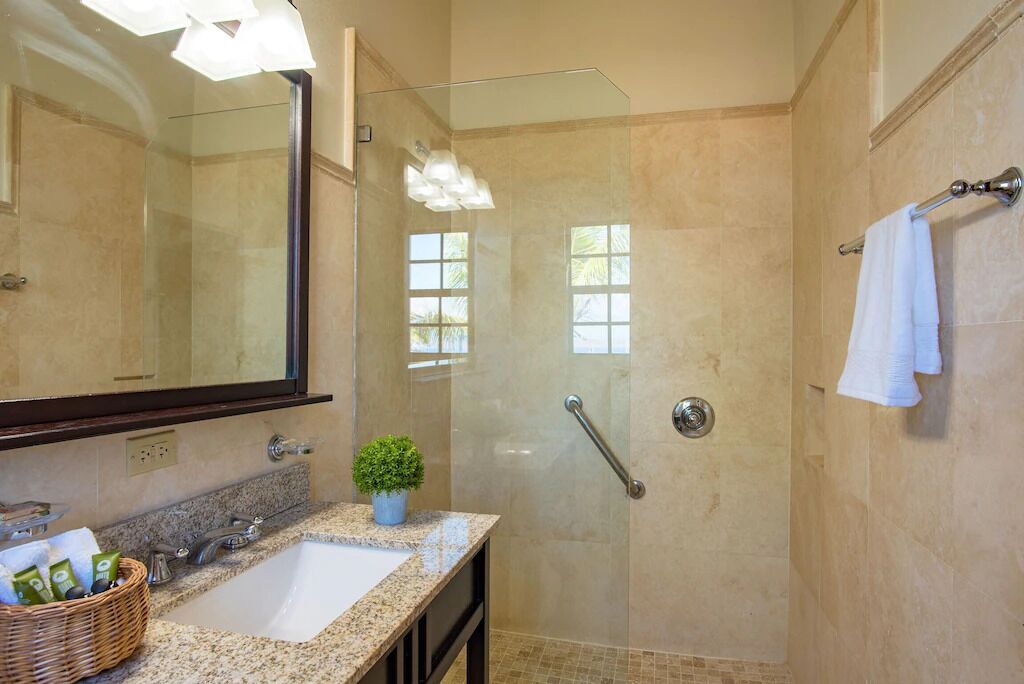 A modern bathroom with a glass-enclosed shower, a large mirror, and a granite countertop.