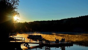 A serene lakeside scene with a dock, wooden chairs, and a bench. - Camp Adirondack at Big Moose Lake (Eagle Bay)