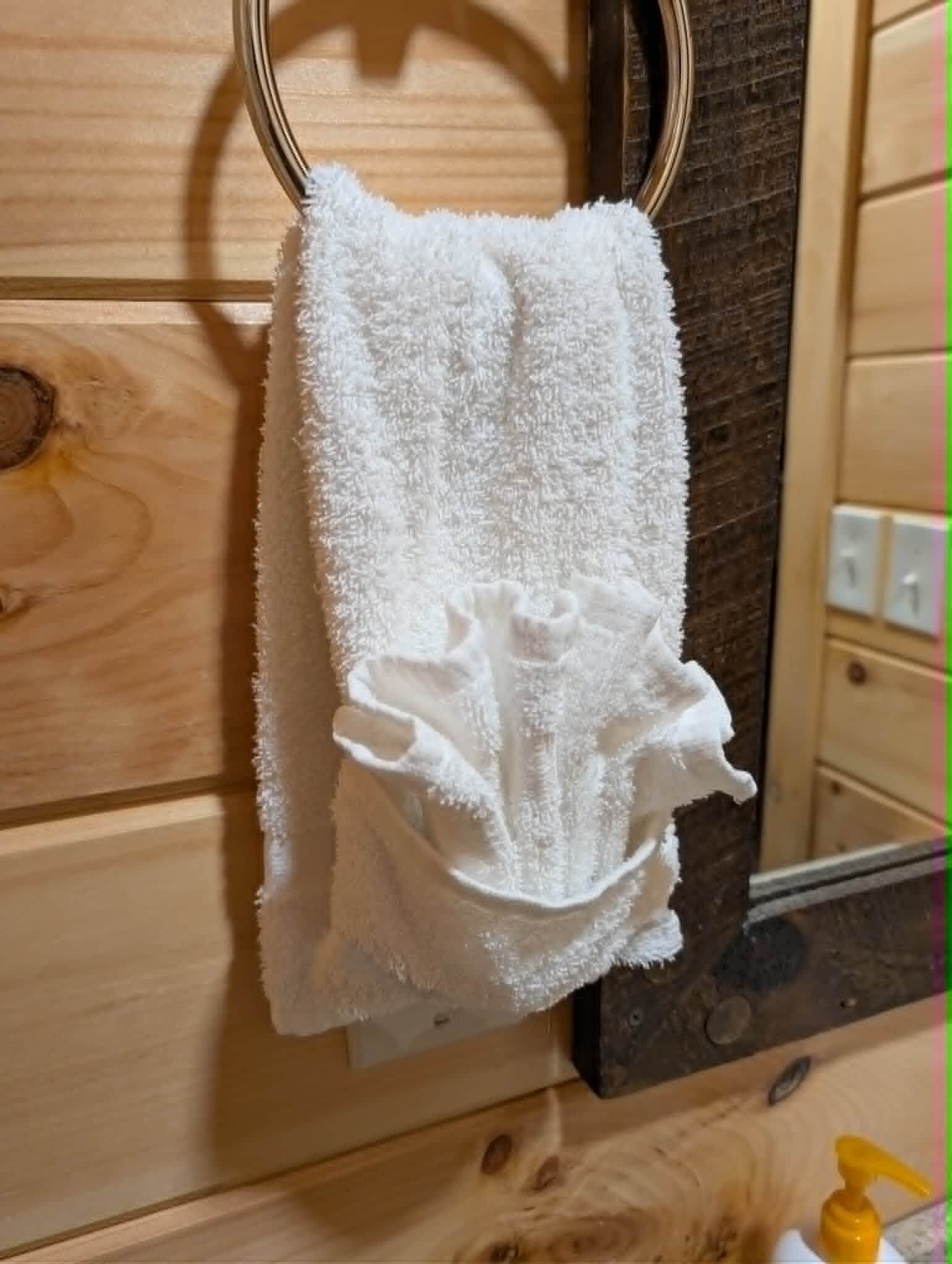 A white towel hanging on a metal hook, a wooden cabinet, and a mirror with a dark frame.