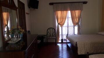 Un dormitorio con cama, una silla, una mesita y un espejo.