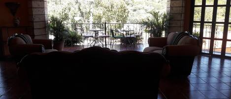 A room with a large window, a sofa, and a dining table with chairs.