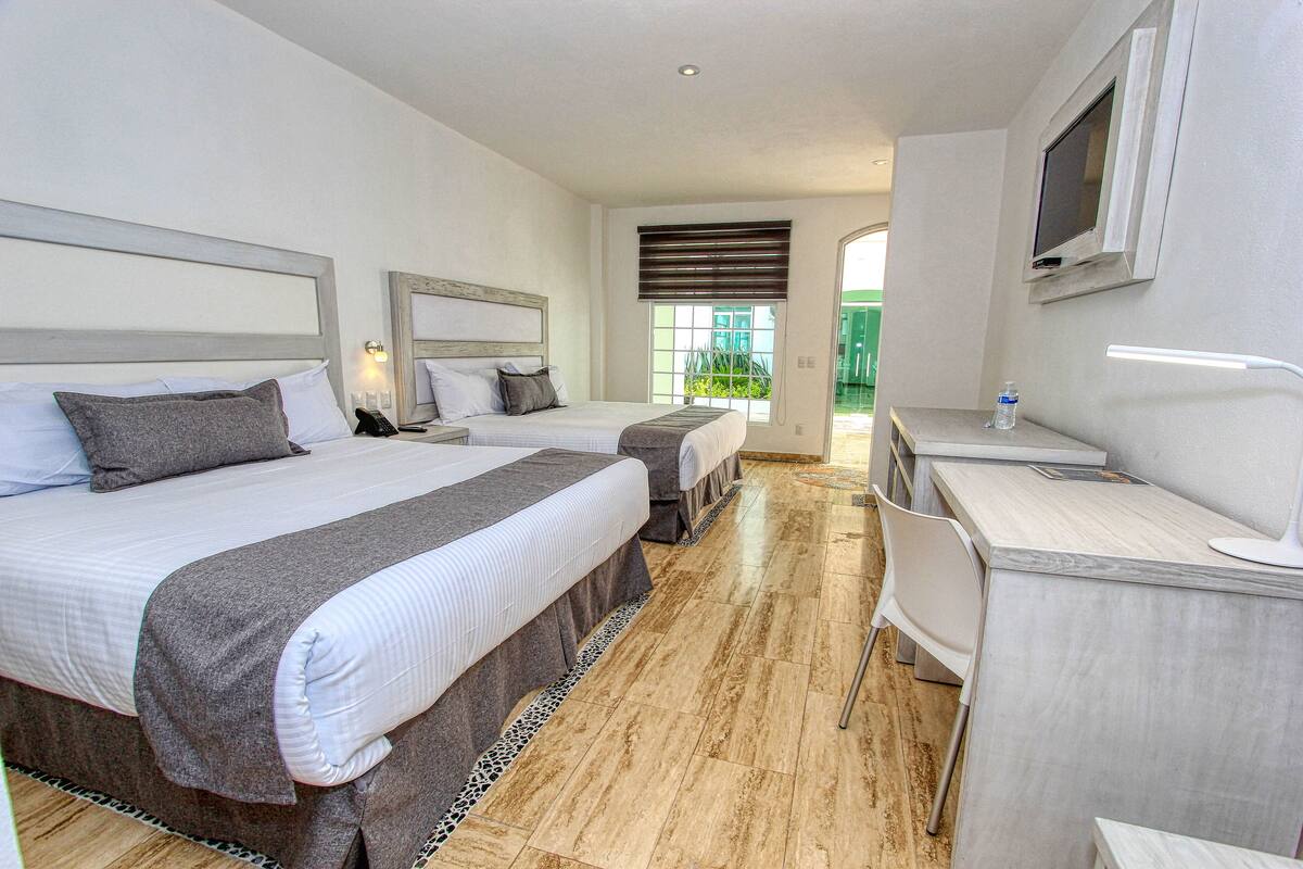 Une chambre d’hôtel avec deux lits, un bureau et une télévision.