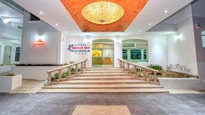 Ein Hotel Eingang mit Treppe, einer Rezeption und einem Schild mit dem Hotelnamen.