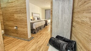 Ein Hotelzimmer mit einem großen Bett, einem Nachttisch, einem Spiegel und einem Duschbereich.