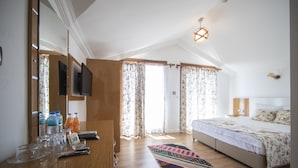 A bedroom with a bed, a desk with a mirror, and a television. - Mandalin Akyaka Hotel (Ula)