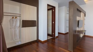A modern hotel room with a wooden floor, a large mirror, a wardrobe with a sliding door, and a television mounted on the wall. - The Reiko Villa Bali (Nusa Dua)