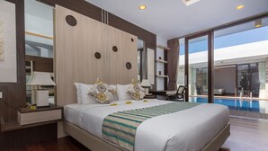 A modern hotel room with a large bed, a nightstand, a desk, and a view of a swimming pool. - The Reiko Villa Bali (Nusa Dua)