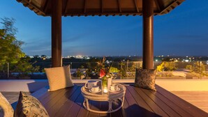 A wooden deck with a round table, two cushions, and a vase with flowers. - The Reiko Villa Bali (Nusa Dua)